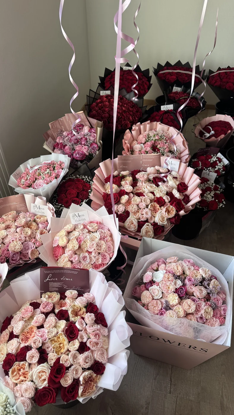 Blandade handbundna buketter med röda och rosa rosor inslagna i rosa och svart papper hos Midosflowers